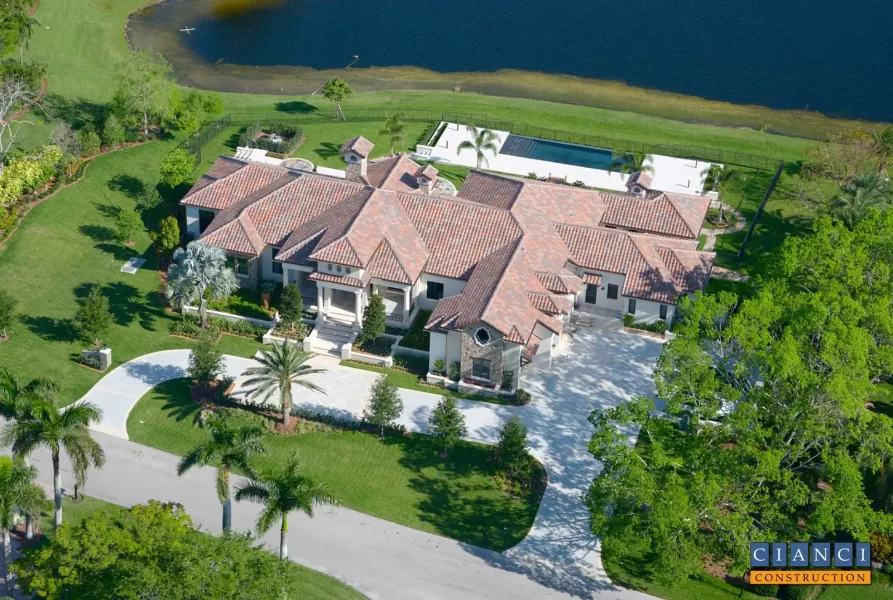 Aerial view of Tuscan Country Estate home from front side with view of patterned concrete driveway and entry.